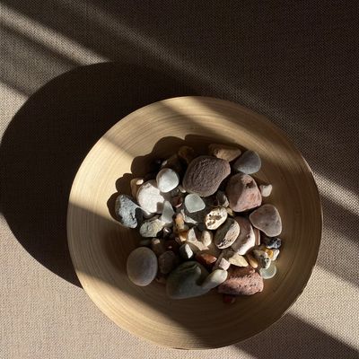 A minimalist composition with a singing bowl and a smooth stone.