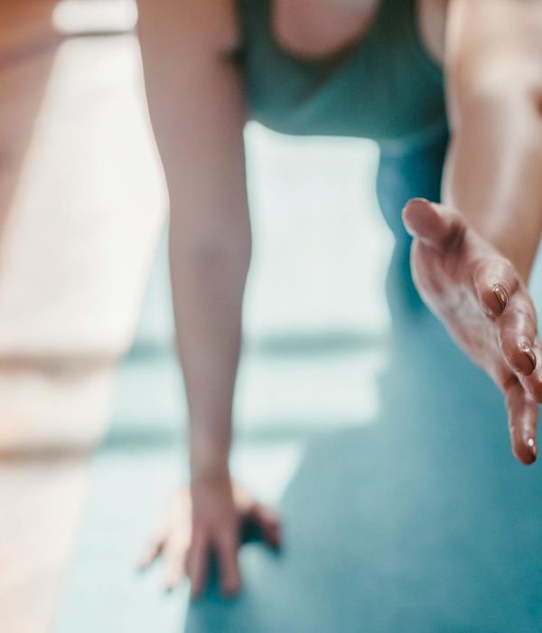 Person in a dynamic yet controlled yoga pose in a spacious, dimly lit room.